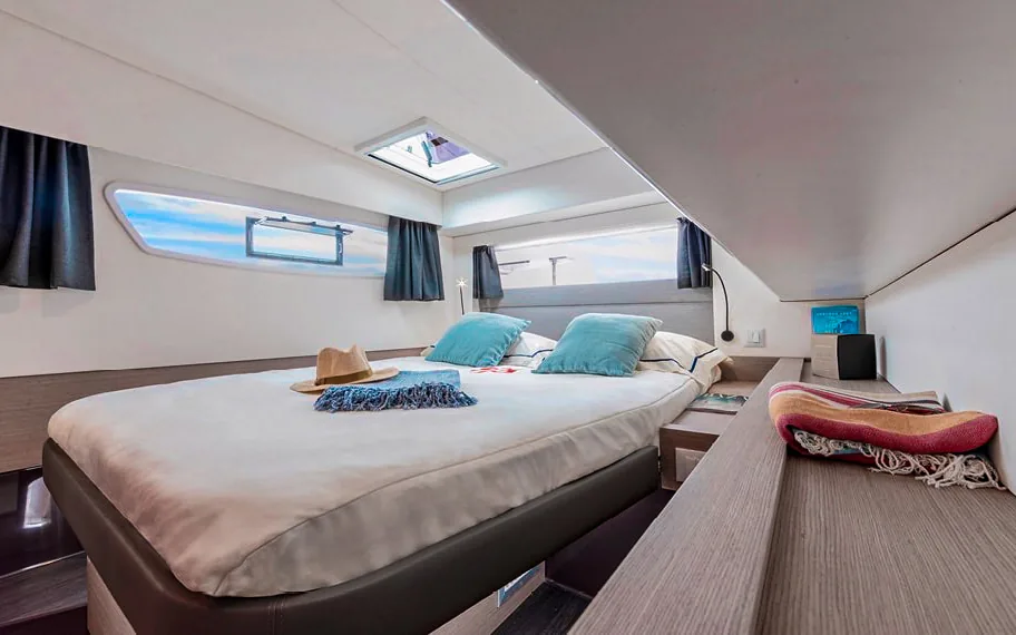 Private double cabin on the Makani catamaran with porthole windows and ocean light.