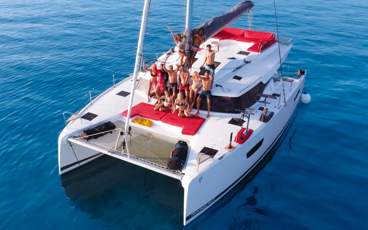 Guests relaxing on the catamaran deck in clear blue water.
